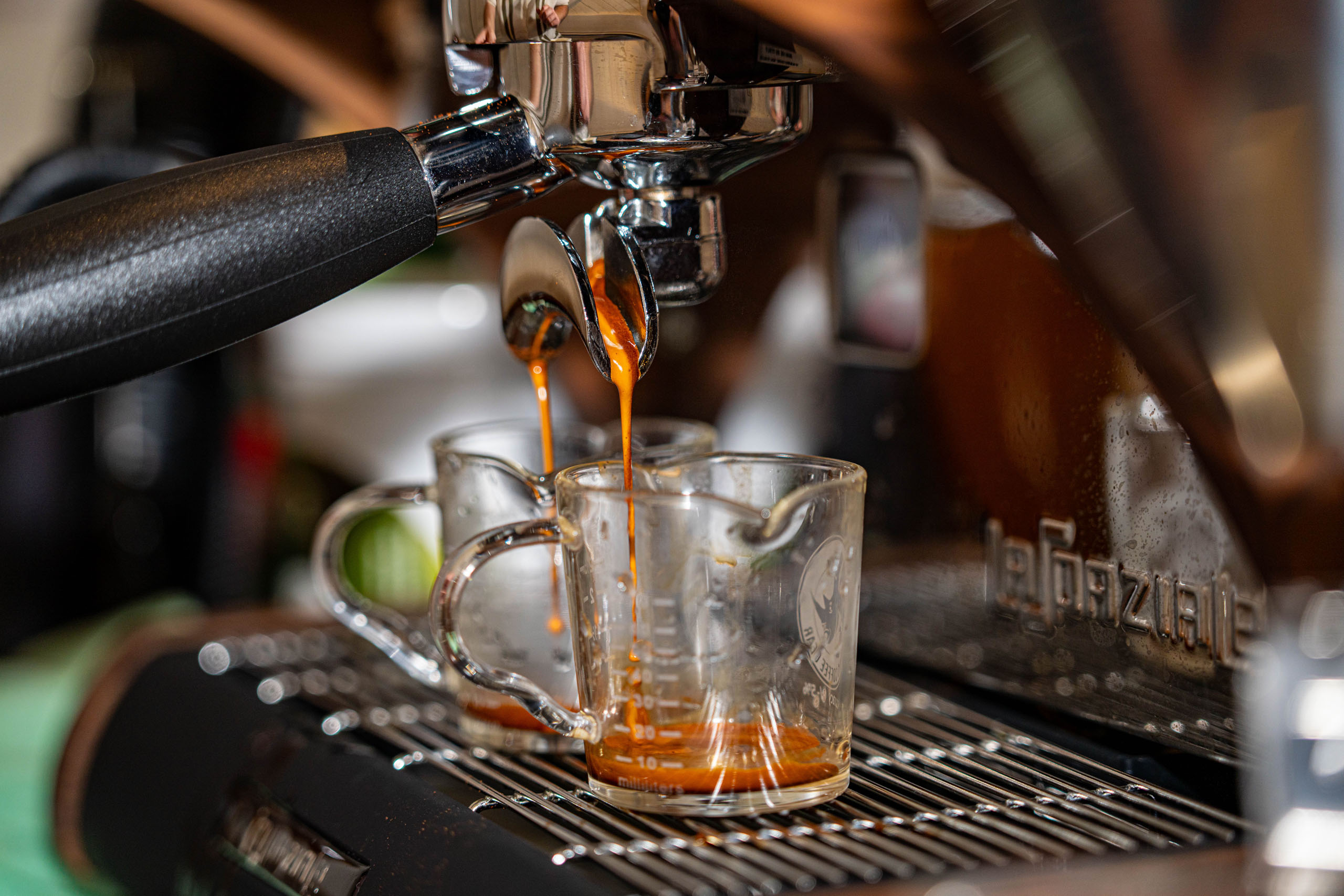 Fresh espresso pulling from a La Marzocco machine into glass shot glasses at a New Mornings Coffee mobile coffee cart event